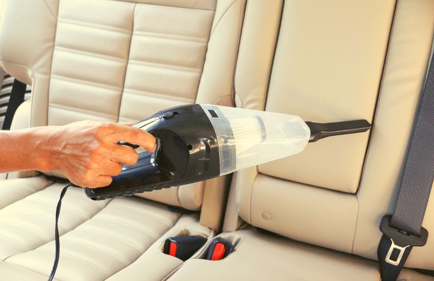 Hand vacuum being used to clean a car seat