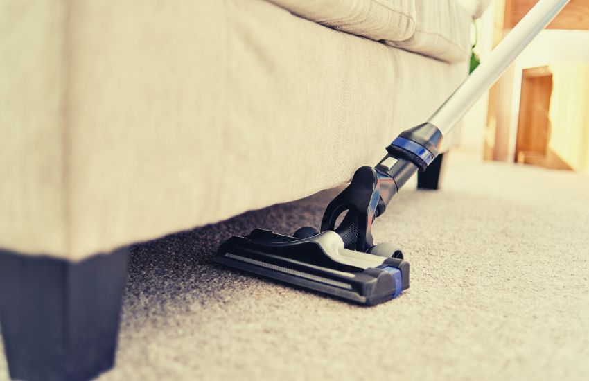 Vaccum cleaning carpet under a couch