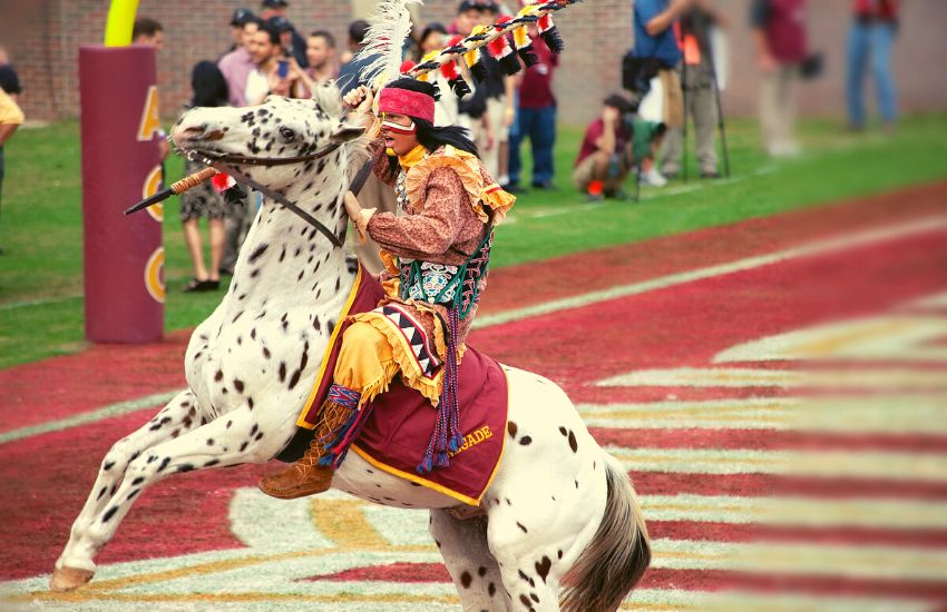 Man in Native American wear riding an Appaloosa horse