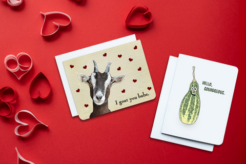 A photo of two Valentine's Cards. One with a goat on, text reads, 'I Goat You.' The other has a gourd on it, text reads 'Hello Gourdgeous.'