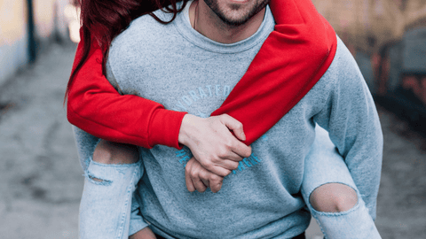 woman piggy backing a man in a city street