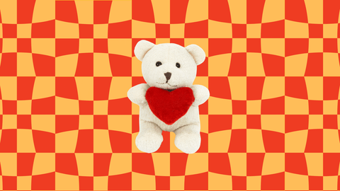 white cuddly toy bear holding red heart on orange and red background