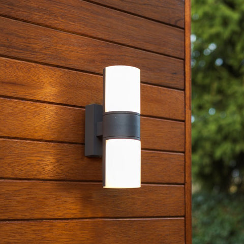 A cylindrical outdoor wall light mounted on a wooden wall.