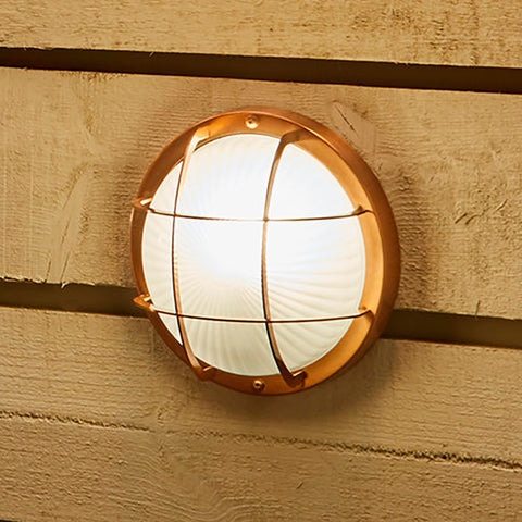A circular nautical light on a wooden background.