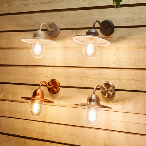 Variations of nautical lights handing on a wooden plank wall.