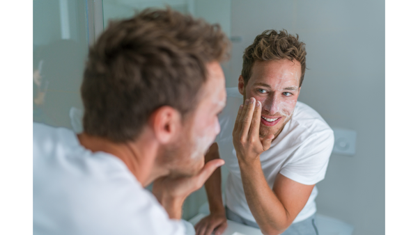 Image of a man applying moisturiser in the mirror