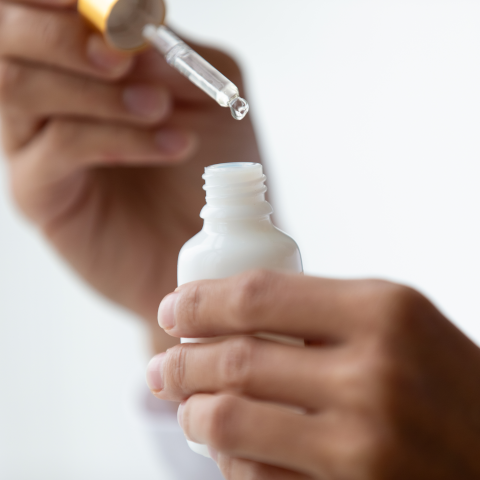 person holding dropper drawing essential oil from bottle
