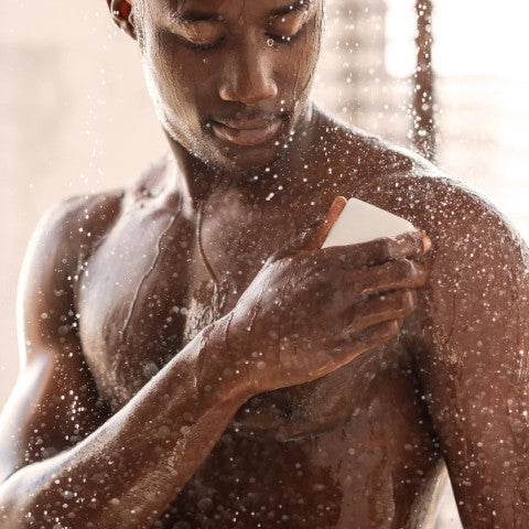 man using soap while showering