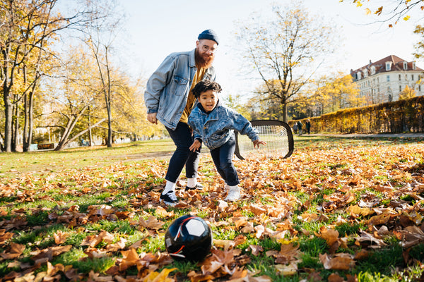 Dad playing soccer with son in park