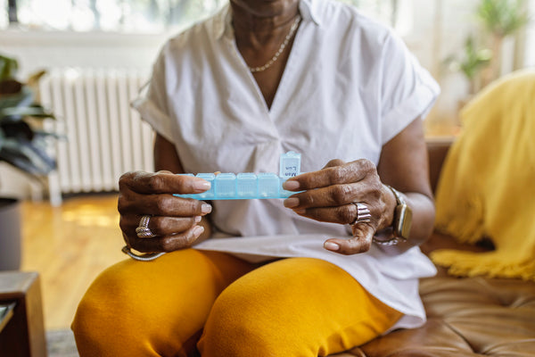 Woman taking daily supplements from a pill organizer