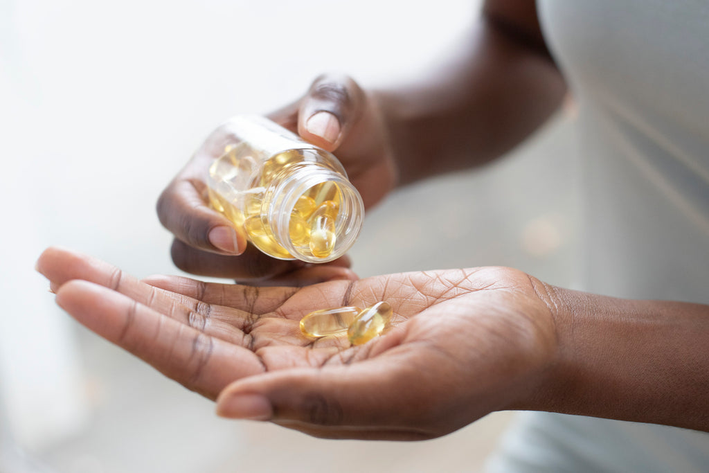 Pouring vitamin D capsules into hand.