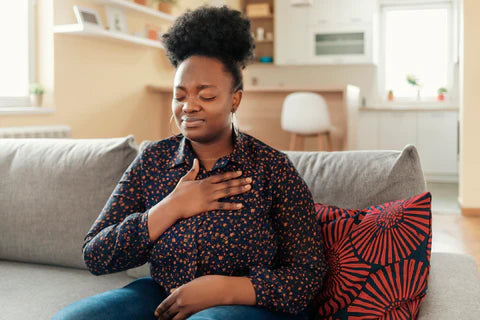 Woman sitting down with eyes closed and one hand on chest