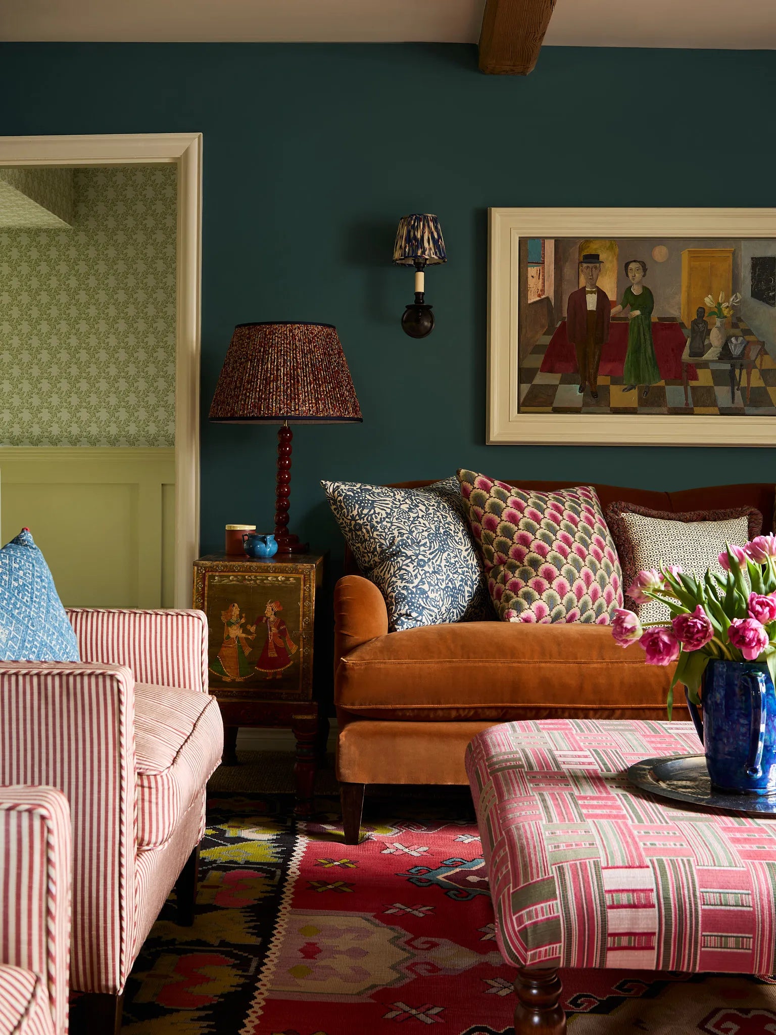 A comfy living room with navy walls, a burnt range sofa and patterned cushions.