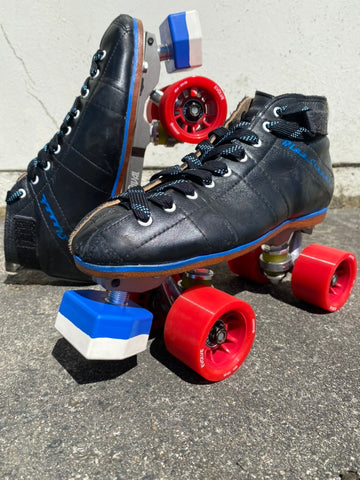 A pair of roller derby skates, with red wheels and blue and white toe stops.