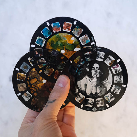 hand holding three retroviewer reels of artwork by brandon boyd