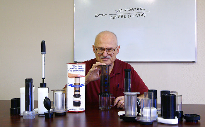 Alan Adler sitting next to AeroPress coffee maker prototypes