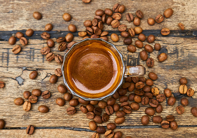 Cafe Cubano in a cup with coffee beans on a wooden table