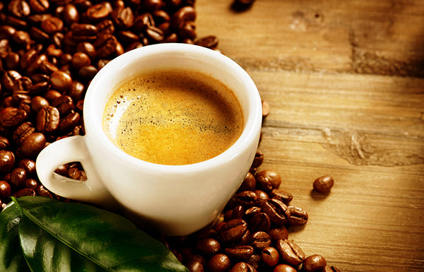 Espresso cup on top of coffee beans on wood table