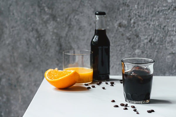 Cold brew coffee next to coffee beans and orange