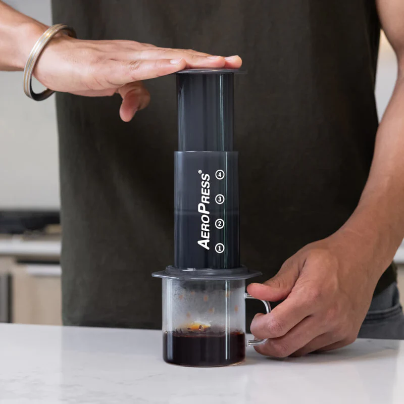 Man brewing coffee with AeroPress Original into glass mug