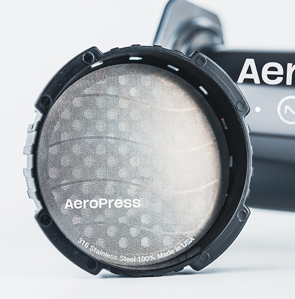 AeroPress stainless steel reusable filter in filter cap next to AeroPress Original