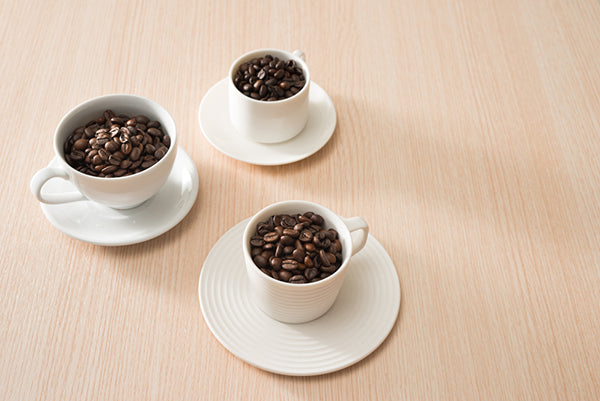 Three white cups of beans on pale table