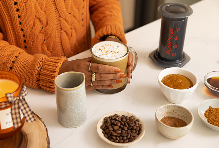 Woman about to enjoy a pumpkin spice latte from her AeroPress Original coffee maker