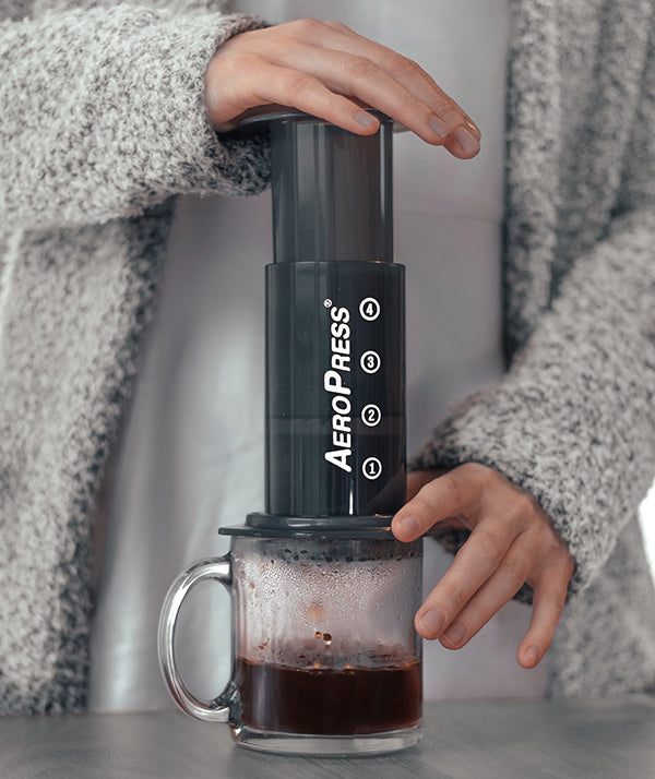 Woman in grey sweater brewing coffee