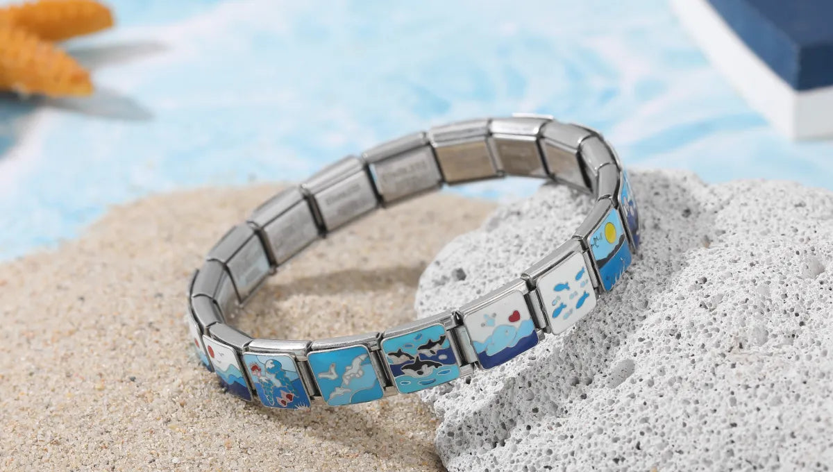 Flat-lay of custom bracelets using ocean-style italian charms including sun, seagulls, and waves.