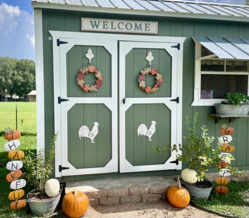 A sage green coop is decorated with fall decorations.