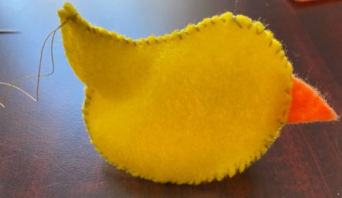 DIY chick craft partially assembled with 2 sides, beak and belly pieces sewn together, ready to be stuffed.