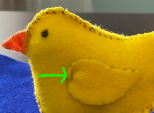 Felt wing pieces are sewn onto the DIY chick craft body at the appropriate wing positions.