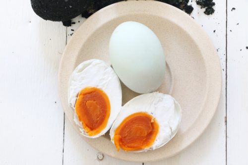 A hard boiled duck egg is cut in half showing a rich orange egg yolk. 
