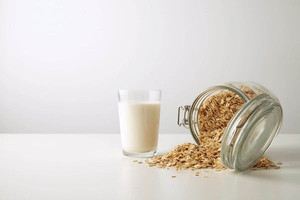 Low calorie oat milk on a table with a jar of oats