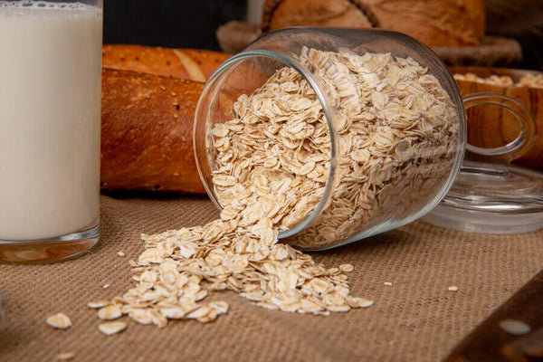 Fibre filled oats on a table next to a glass of oat milk