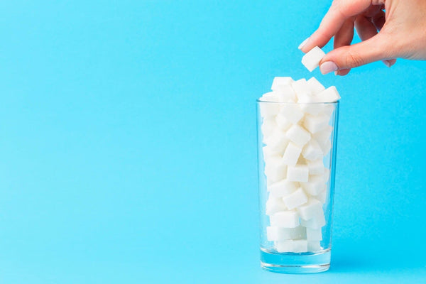 Hand placing sugar into a milk glass