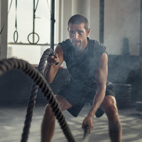 Fit man doing battling ropes exercise