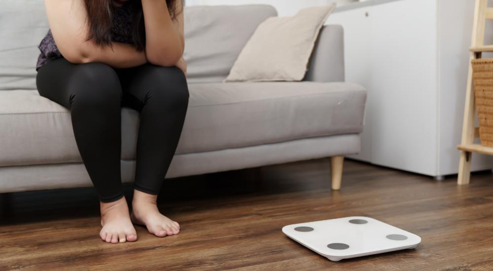 Woman sitting on couch upset about the weight on a scale