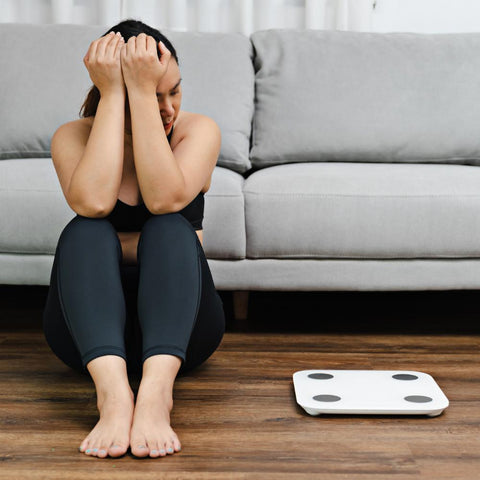 Discouraged woman looking at weighing scale