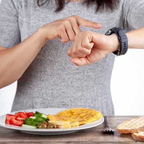 Woman looking at wristwatch before starting meal. Intermittent fasting