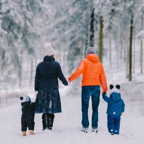 Young couple and their two children enjoying a walk outdoors in the snow