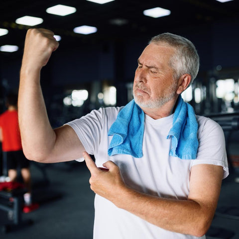 Older man at the gym flexing his arm muscles