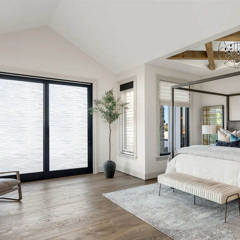 A bedroom with a bed, chandelier, and sliding glass door