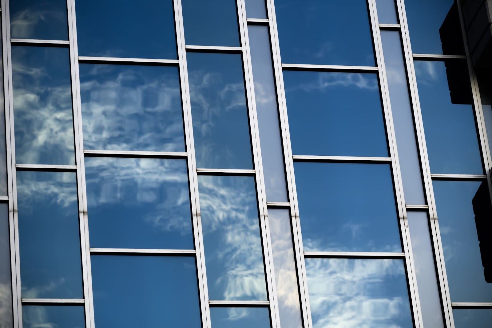 A building with sky reflection in windows, showcasing Nano Ceramic Tint on business windows, eco-friendly