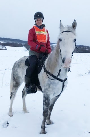 woman sitting on a gray Tennessee Walking horse wearing a Freeform treeless saddle in the snow.