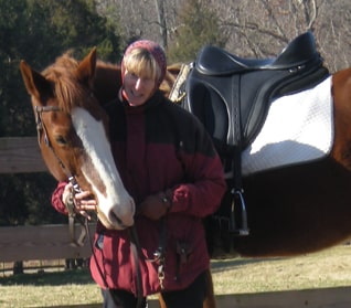 Woman standing with her blaze faced sorrel horse wearing a Freeform treeless saddle.