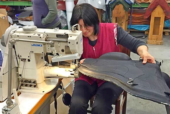 Italian craftswoman hand stitching the binding on a Freeform Classic Tressless Saddle in Italy.
