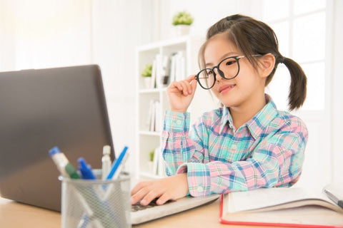 Child wearing glasses staring at computer