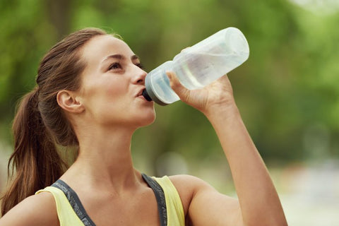 female runner drinking from water bottle