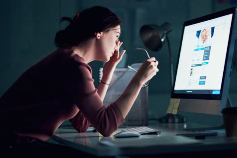 Someone staring at a computer screen and rubbing their eyes